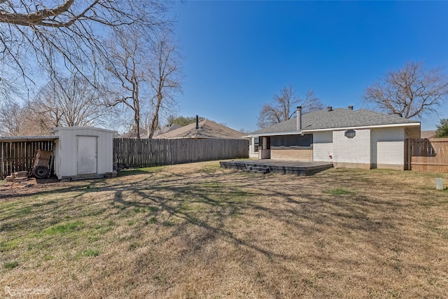 view of yard featuring a fenced backyard, a storage unit, a deck, and an outbuilding