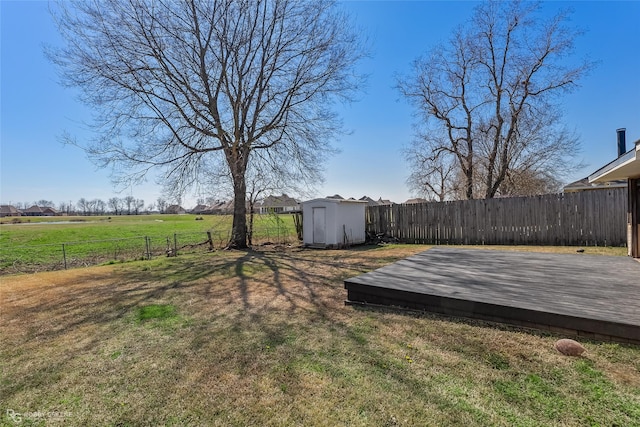 view of yard featuring a storage shed, a fenced backyard, a wooden deck, and an outbuilding