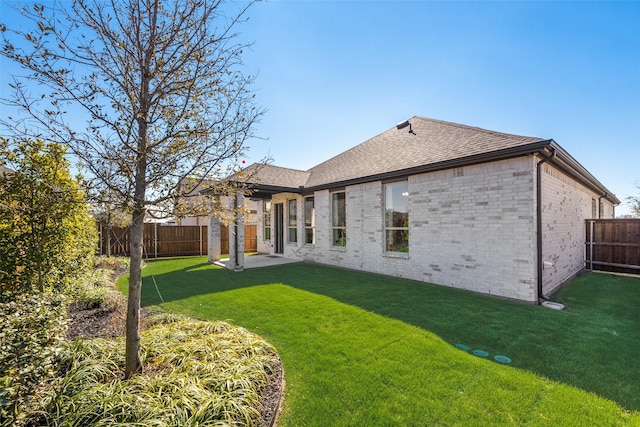 back of property featuring brick siding, a lawn, and a fenced backyard