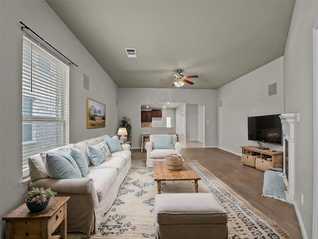 living area with a ceiling fan, baseboards, visible vents, and wood finished floors