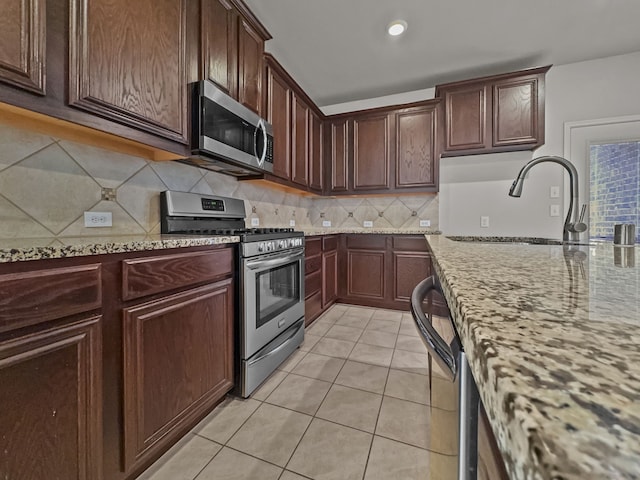 kitchen with light stone counters, light tile patterned floors, tasteful backsplash, appliances with stainless steel finishes, and a sink