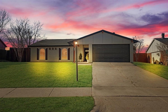 ranch-style home with an attached garage, a front lawn, concrete driveway, and brick siding