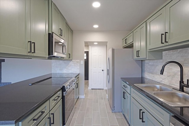 kitchen with stainless steel appliances, dark countertops, a sink, and backsplash