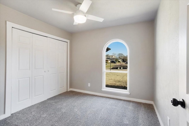 unfurnished bedroom featuring a ceiling fan, carpet, a closet, and baseboards