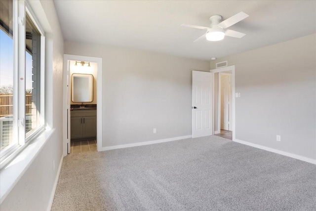 unfurnished bedroom featuring ensuite bath, baseboards, visible vents, and light colored carpet