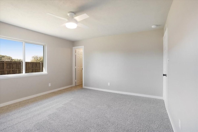 empty room with ceiling fan, carpet, and baseboards