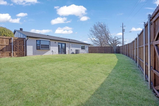 view of yard with french doors, central AC unit, and a fenced backyard