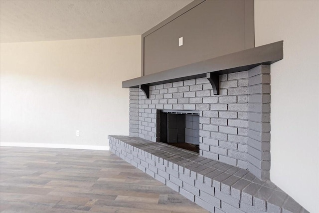 details featuring a fireplace, a textured ceiling, baseboards, and wood finished floors