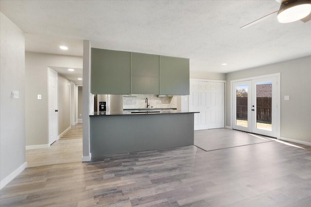 kitchen with dark countertops, french doors, light wood-style floors, stainless steel refrigerator with ice dispenser, and backsplash