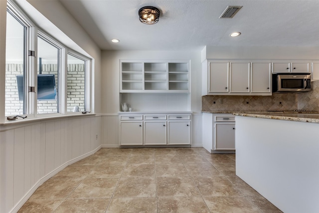 kitchen featuring visible vents, stainless steel microwave, tasteful backsplash, and light tile patterned flooring