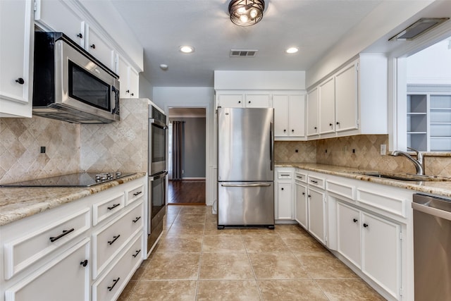 kitchen with appliances with stainless steel finishes, visible vents, a sink, and white cabinetry