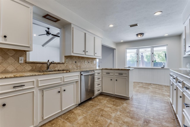 kitchen with a peninsula, a sink, visible vents, stainless steel dishwasher, and wainscoting