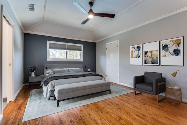 bedroom featuring crown molding, lofted ceiling, visible vents, light wood-style flooring, and baseboards