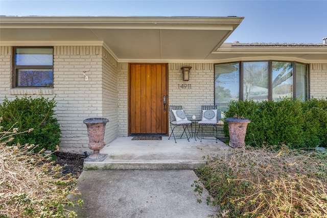 entrance to property featuring covered porch and brick siding