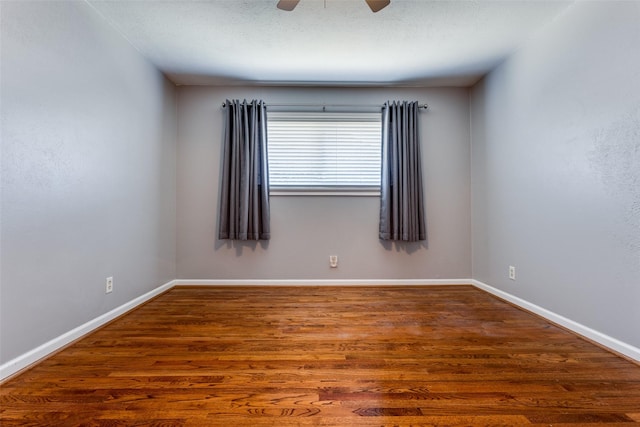 unfurnished room featuring ceiling fan, wood finished floors, and baseboards