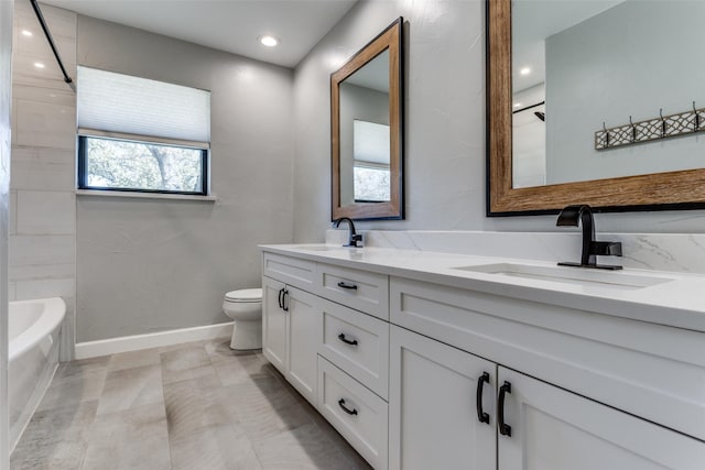 bathroom with double vanity, a bathtub, a sink, and toilet