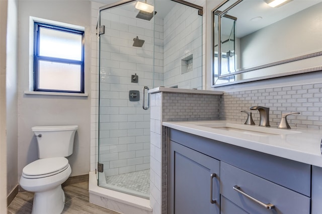 full bathroom featuring a stall shower, toilet, wood finished floors, vanity, and backsplash