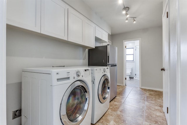 laundry room featuring light tile patterned flooring, baseboards, cabinet space, washing machine and clothes dryer, and track lighting