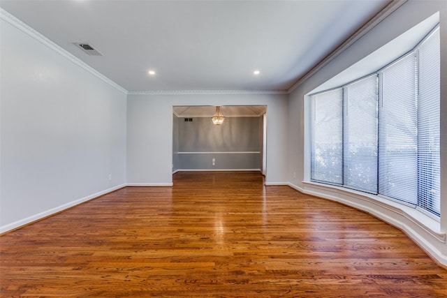 empty room featuring ornamental molding, wood finished floors, visible vents, and baseboards