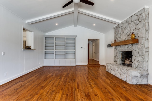 unfurnished living room featuring baseboards, ceiling fan, wood finished floors, vaulted ceiling with beams, and a stone fireplace