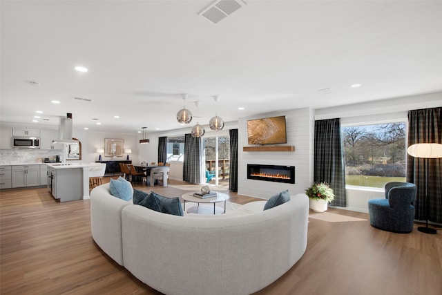 living room featuring light wood finished floors, a fireplace, visible vents, and recessed lighting