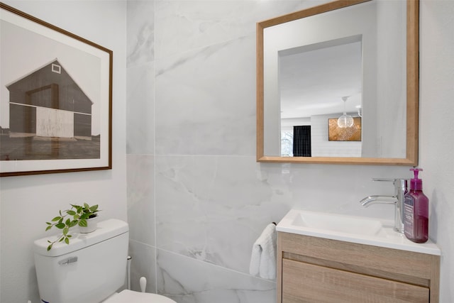 bathroom featuring toilet, tile walls, and vanity