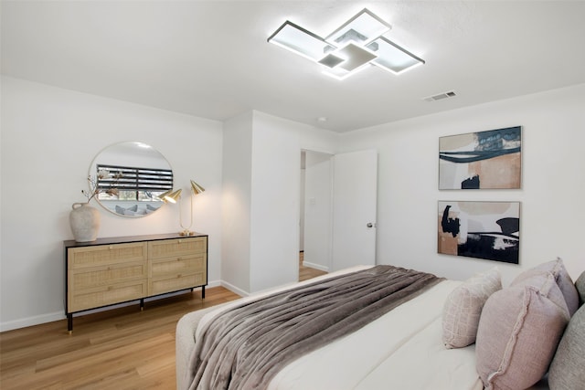 bedroom with wood finished floors, visible vents, and baseboards