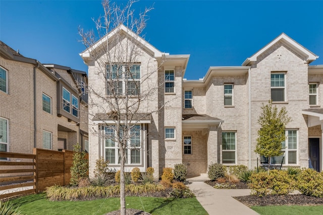 view of front of house featuring brick siding and fence