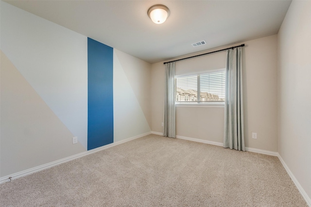 spare room with baseboards, visible vents, and light colored carpet