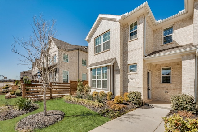 exterior space featuring a front yard, brick siding, and fence