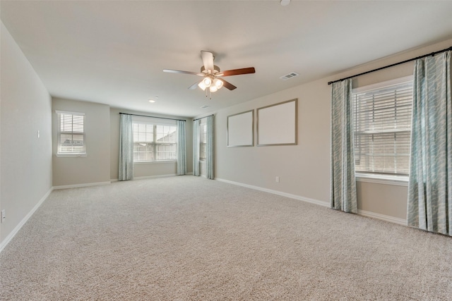 carpeted spare room with ceiling fan, visible vents, and baseboards