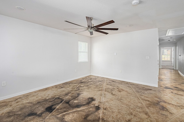 unfurnished room featuring a ceiling fan, attic access, and baseboards