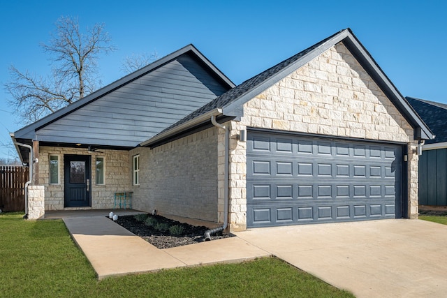 view of front of home featuring covered porch, fence, a garage, stone siding, and driveway