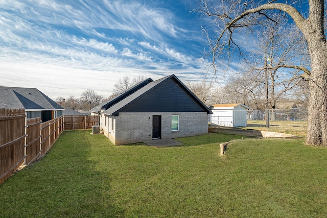 rear view of house with a yard, brick siding, and a fenced backyard