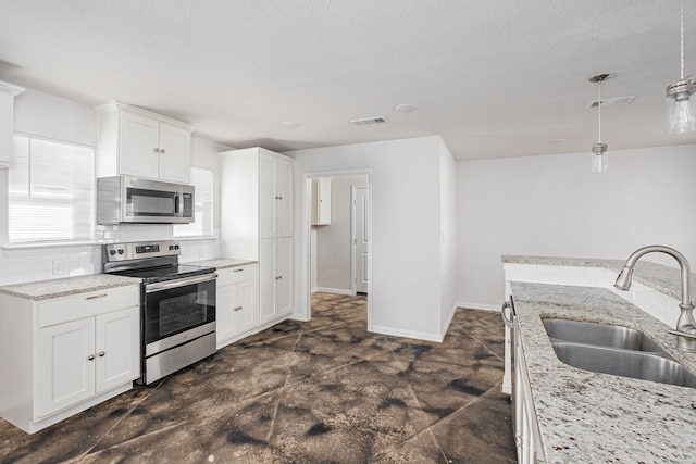 305 W Johnson St, Denison, TX 75020 - kitchen featuring appliances with stainless steel finishes, a sink, decorative backsplash, white cabinets, and hanging light fixtures