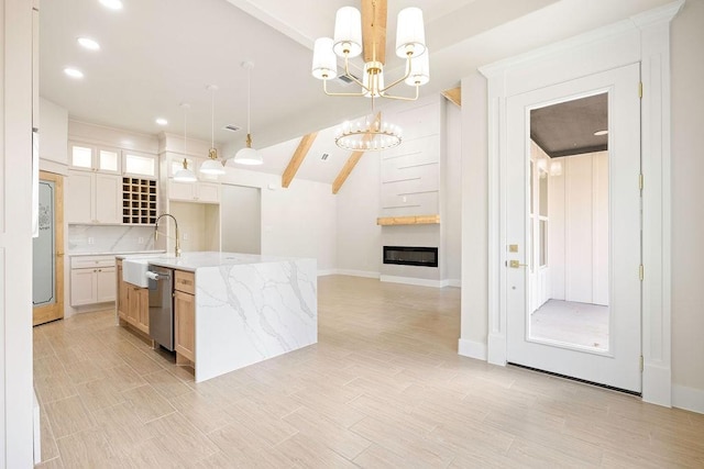 kitchen with a large fireplace, dishwasher, vaulted ceiling with beams, an inviting chandelier, and a kitchen island with sink