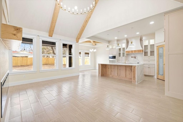 kitchen featuring a notable chandelier, open floor plan, light countertops, beam ceiling, and glass insert cabinets