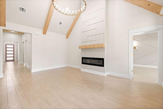 unfurnished living room featuring visible vents, an inviting chandelier, light wood-style floors, a glass covered fireplace, and beamed ceiling