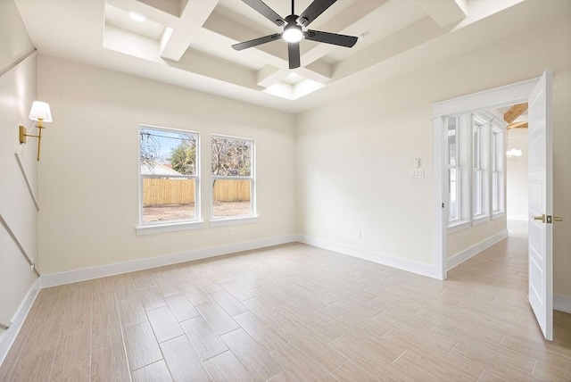 empty room with a ceiling fan, coffered ceiling, light wood-style flooring, and baseboards