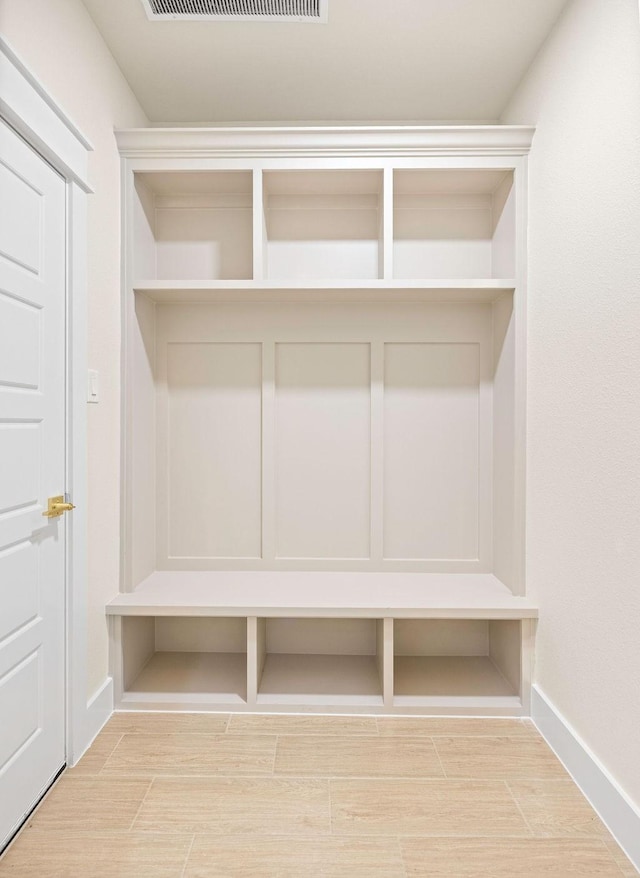 mudroom with wood finish floors, visible vents, and baseboards