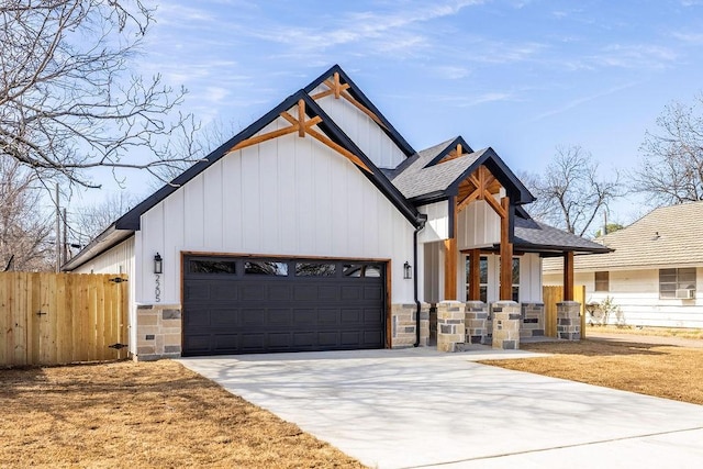 modern farmhouse style home with an attached garage, fence, stone siding, driveway, and roof with shingles