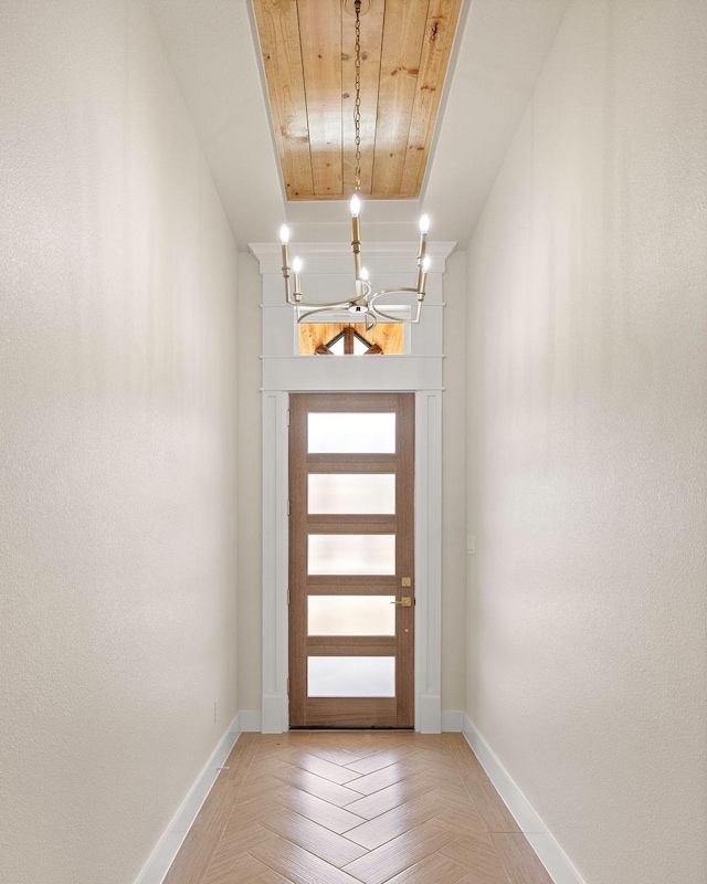 doorway with an inviting chandelier and baseboards