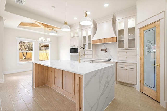 kitchen with tasteful backsplash, visible vents, a sink, premium range hood, and black electric cooktop