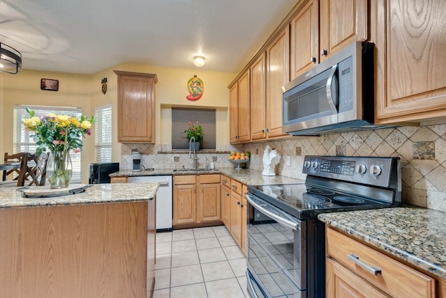 kitchen featuring stainless steel appliances, light tile patterned flooring, a sink, and light stone countertops