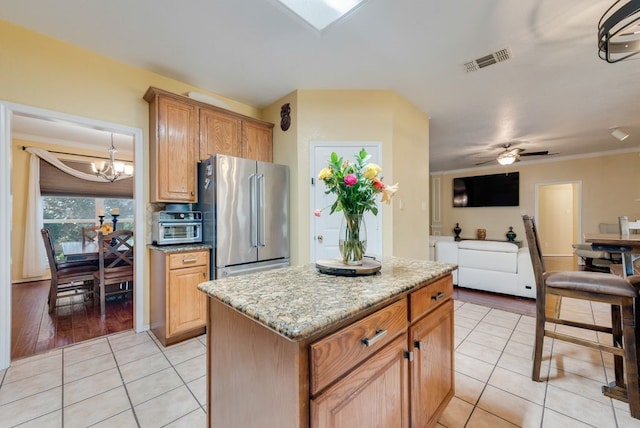 kitchen featuring crown molding, light tile patterned floors, visible vents, high quality fridge, and ceiling fan with notable chandelier