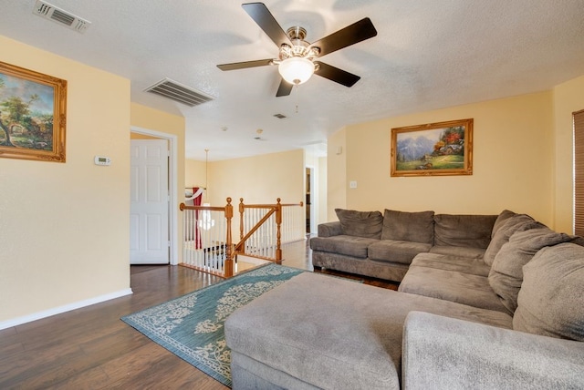 living room with a textured ceiling, dark wood finished floors, visible vents, and baseboards