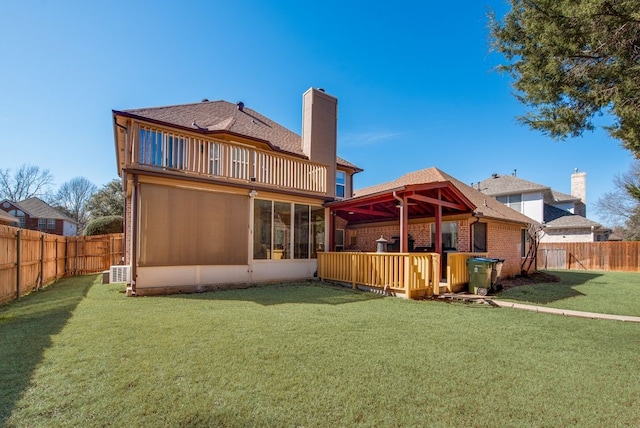 rear view of property with a fenced backyard, a balcony, brick siding, a yard, and a chimney