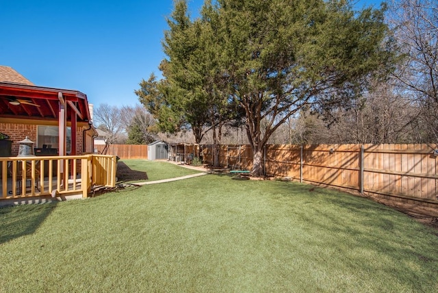 view of yard with a storage shed, a fenced backyard, and an outbuilding