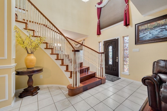 tiled foyer featuring baseboards, crown molding, stairway, and a high ceiling