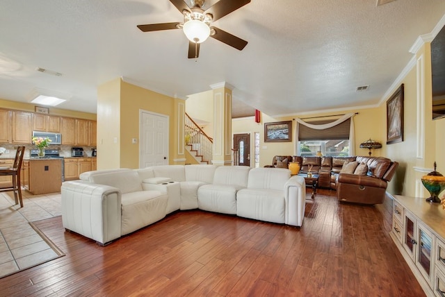 living room featuring hardwood / wood-style flooring, stairway, visible vents, and ornate columns